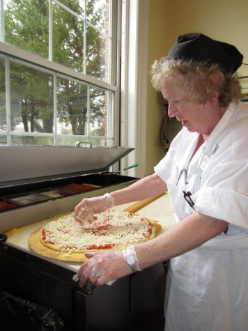 Pizza-maker Peg Bates makes a cheese pizza for lunch on Wednesday.  She enjoys making BLT pizzas most because they are easy to make. They also happen to be her favorite pizza to eat. CHELSEA FLEISCHMAN/THE CAMPUS.