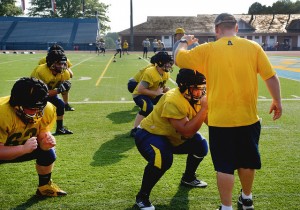 AMASA SMITH/THE CAMPUS Coach Ryan Jones helps Tyler Seibert, ‘16, during football practice at Robertson Field on Tuesday Aug. 26, 2014..