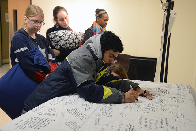 Alex Marrero, ‘18, writes a message on the mattress located in the Campus Center on Wednesday, Oct. 29 for the Carry the Weight movement to support survivors of sexual and domestic violence.