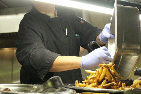 A Brooks Dining Hall cook and server prepares french fries for the grill station on Wednesday, Oct. 28, 2015. 