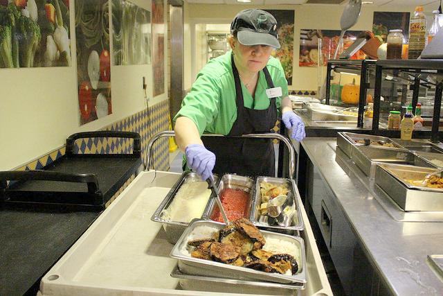Patty Ann Catilina, a server, cleans up leftover food from a buffet at Brooks Dining Hall after the dinner rush on Wednesday, Oct. 28, 2015. 