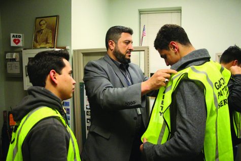 Director of Public Safety Ali Awadi adjusts the vest of Hamza Masaeed, ’20, a member of the Gator Patrol Service, a new service of students working with the Office of Public Safety, before heading for his shift on Nov. 4, 2016. Members of the GPS divide into groups and patrol different parts of campus and assist Public Safety in ensuring the safety and well-being of students, Awadi said.  Awadi said the students of the GPS each work two or three hour shifts between 8 p.m. and 2 a.m. throughout the week. He said their role is largely to help students in need of assistance and alert Public Safety to any potentially hazardous situations.  As the GPS becomes more visible, Awadi said he hopes students will accept that they are there to help.  “We want to make sure the campus embraces them,” Awadi said. 