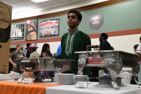 Dipto Mukherjee, ’19, stands ready to serve attendees at the Indian food table. Dishes served included potato curry and mishti pulao. 