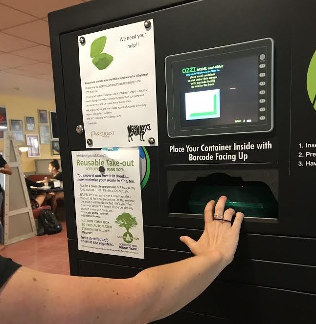 Sustainability Coordinator Kelly Boulton, ’02, places a reusable to-go box in the McKinley’s Food Court OZZI machine. When boxes are placed in the slot, the barcode on the box is scanned, and a token is released in return.