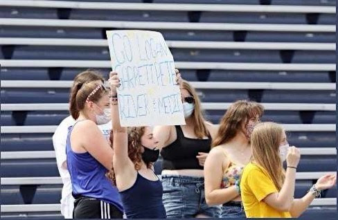 Students cheer on athletes with a sign. After the fall competitive season was completely canceled, a modified spring schedule was introduced, including student attendance in the stands