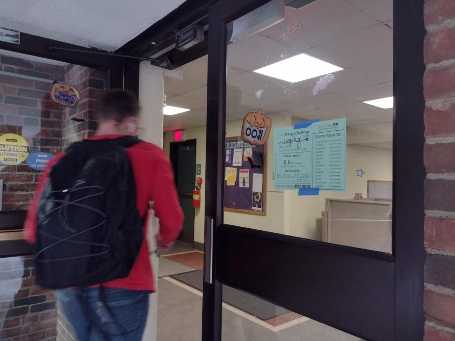 A student enters Baldwin Hall, next to a posting of the results of the Energy Challenge. Baldwin was the lowest hall to reduce consumption; North Village I had no change and five other halls increased consumption.