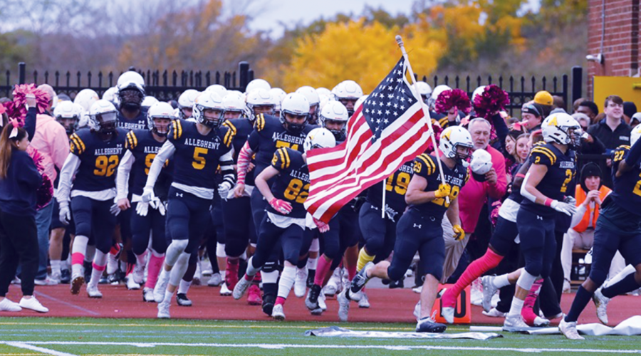 Photo contibured by Ed Mailliard.
The Allegheny Football team takes the field as they are cheered on by cheerleaders and fans. Players and cheerleaders sport various articles of pink clothing in support of Breast Cancer Awareness Month.