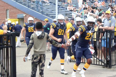 Elijah Roberson, 13, son of Dean of Diversity, Equity and Inclusion Heather Moore Roberson, high-fives David Babb, ’25, as the team runs out of the locker room for the second half.