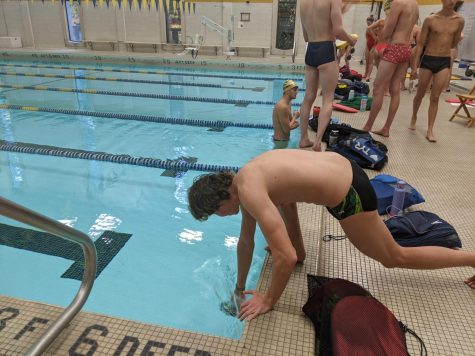 Emmet Fluharty, ’26, wets his swimming cap minutes before jumping into the water during practice on Wednesday, Oct. 19.