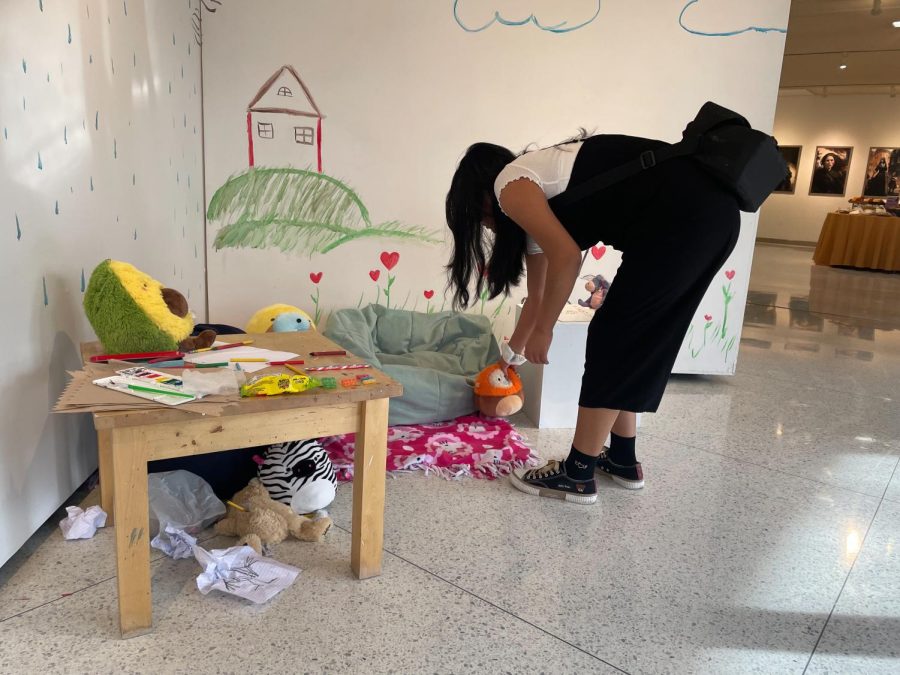 Stephanie Alfaro-Alcaide, ’24, adjusts a set piece at her display. Taking inspiration from child abuse prevention agency Amigos for Kids’ exhibit “Broken Crayons,” Alfaro-Alcaide hid messages of abuse in drawings and notebooks as a child might.
