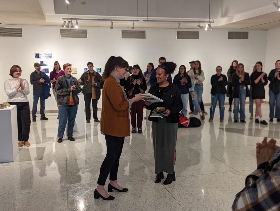 Eila V. Bush Endowed Professor of Art Heather Brand presents Rahwa Weldemichael, ’23, an award for best digital art or photography in the show. Weldemichael also recieve an honorable mention from the gallery’s juror, Kris Rumman, a New York City-based Palestinian-American artist.