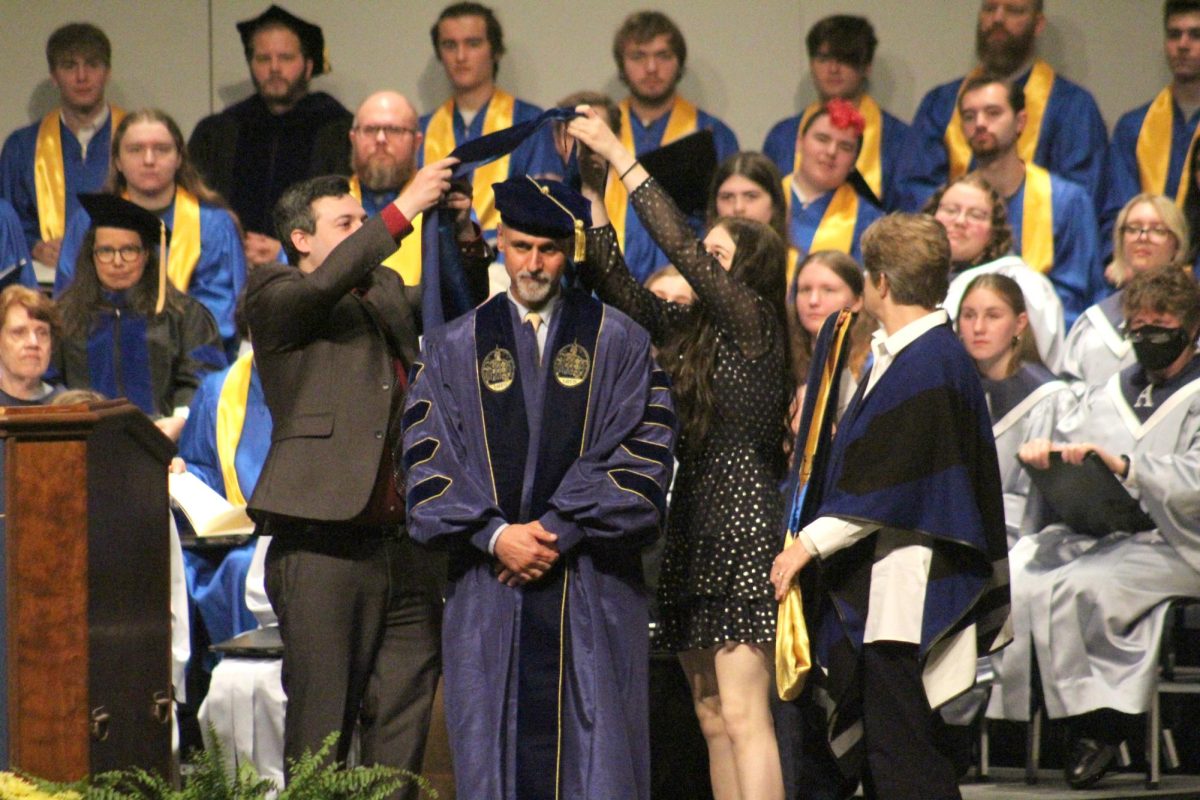 Cole’s children change his hood during his invocation while Cole’s wife, Visiting Assistant Professor of Psychology Nancy Frambes, ’87, looks on.
