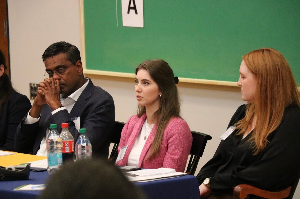 Morgan Dukman, ’23, responds to an audience question at the “Board of Visitors Roundtable: From Classroom to Boardroom - Embracing AI’s Impact” in the Henderson Auditorium in Quigley Hall on Friday, Sept. 19.  Dayan Abeyaratne, ’94, (left) and Lauren Odrechowski, ’10, (right) listen to Dukman’s answer. 