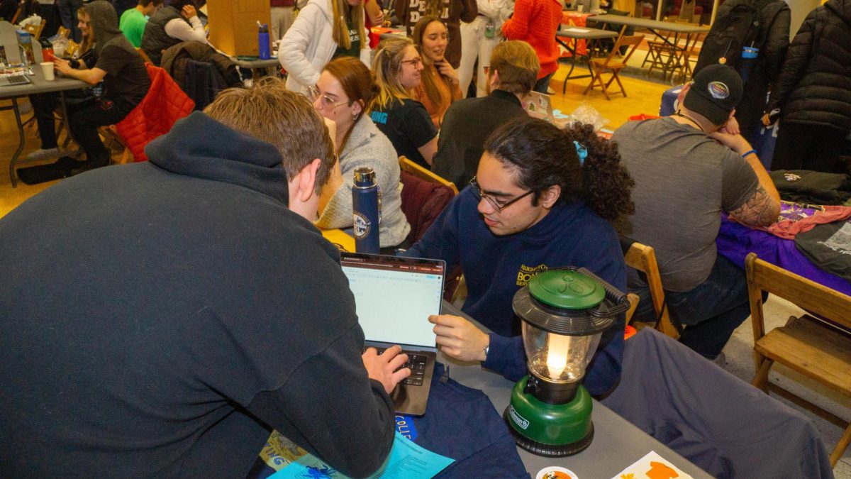 Aaron Navarrete, ’29, an Outing Club leader, signs up an interested student for the club email list at the winter involvement fair in the Henderson Campus Center lobby on Thursday, Jan. 15.