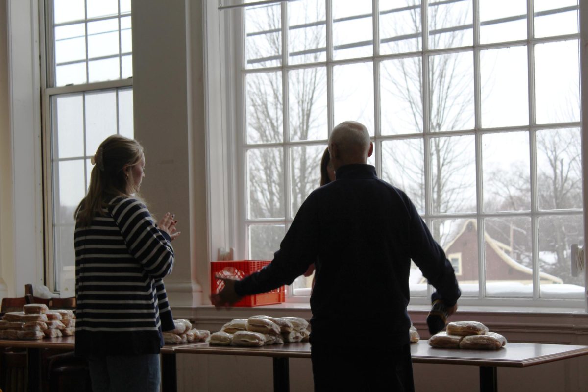 President Ron Cole, '87, (right) speaks with  Kylie Thompson, '27 (left), and Parkhurst Marketing Coordinator Cecily Greggs (hidden behind Cole) over a table stacked with cold to-go sandwiches in Brooks Dining Hall at noon on Tuesday, Jan. 27.