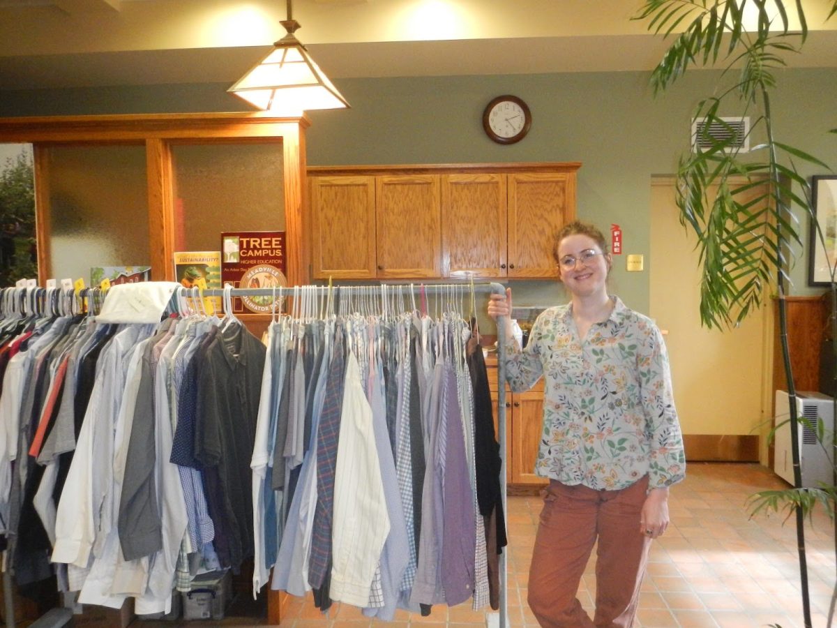 Sustainability Manager Madeline Yeatts stands next to a rack of professional clothing that students have access to through the Gator Success Closet.